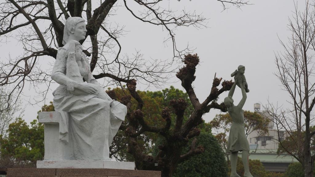 Two statues depicting women and children, one seated and one standing, at Nagasaki Peace Park.