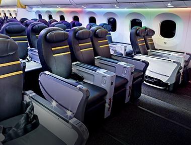 An empty airplane cabin with blue seats and rainbow-colored mood lighting.