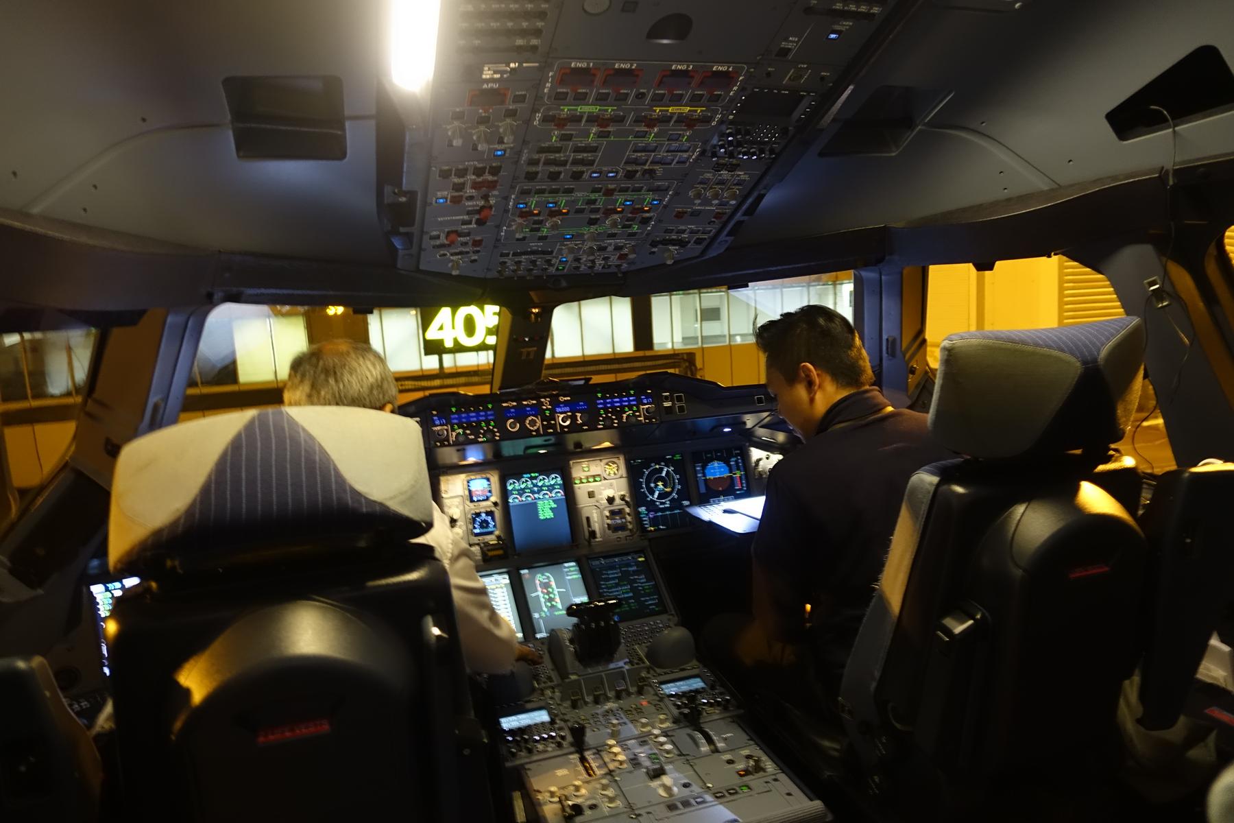 The illuminated cockpit of a Malaysia Airlines A380 with two pilots at the controls.