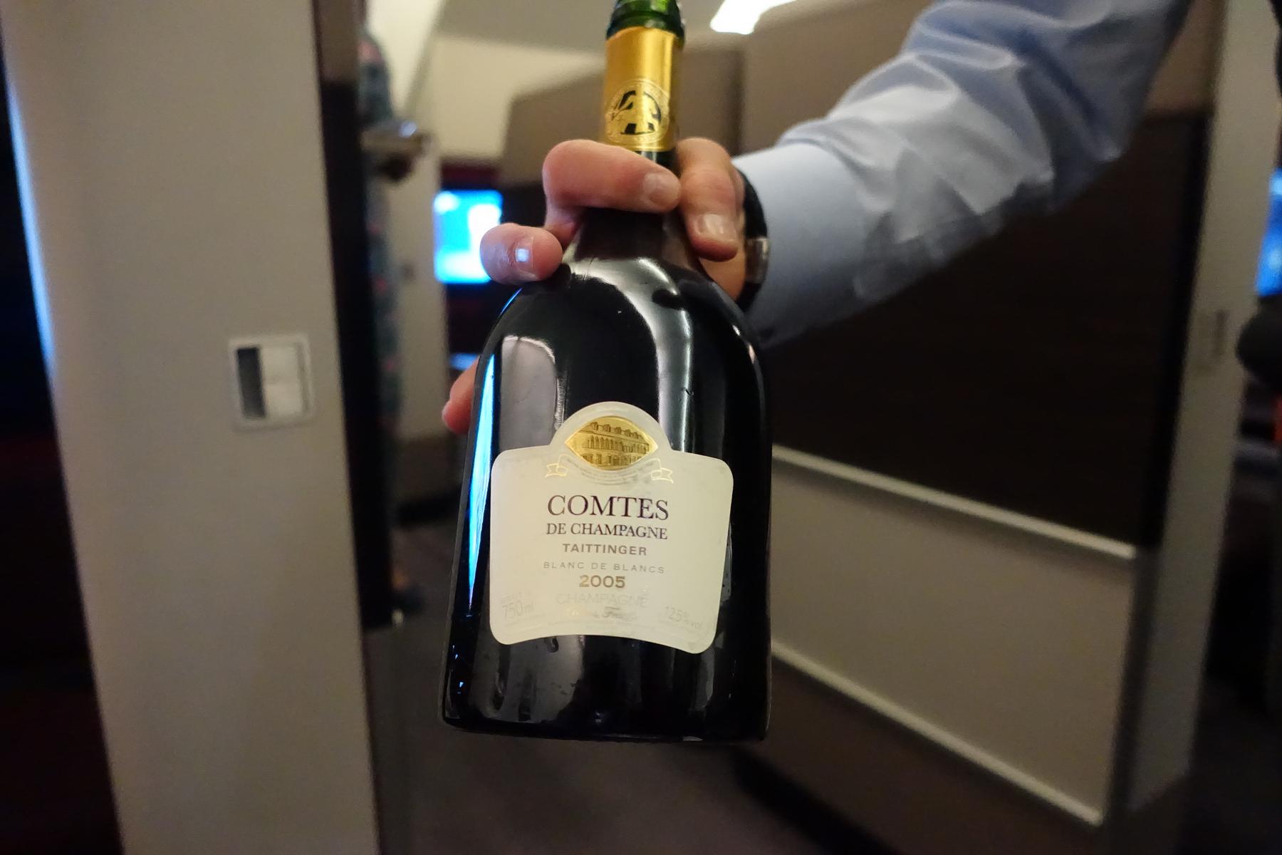 A hand holds a bottle of Taittinger Comtes de Champagne 2005.