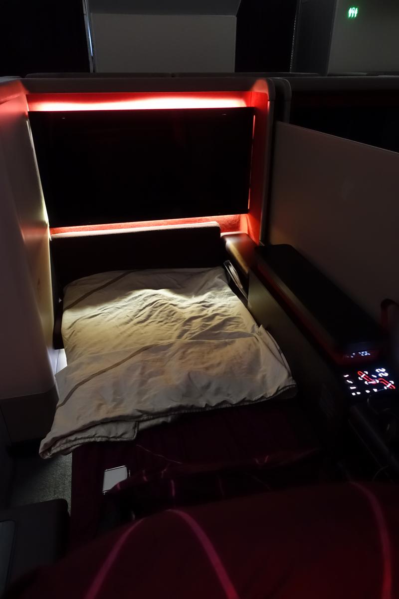 Malaysia Airlines A380 First Class suite with a made-up bed and red mood lighting.