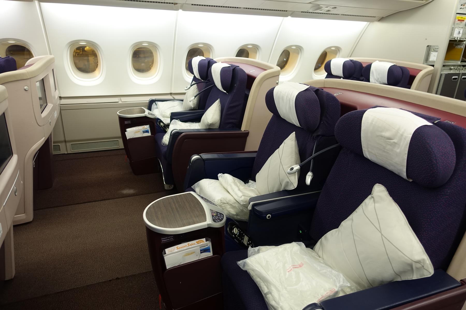 Interior view of Malaysia Airlines A380 First Class cabin with multiple purple and blue seats.