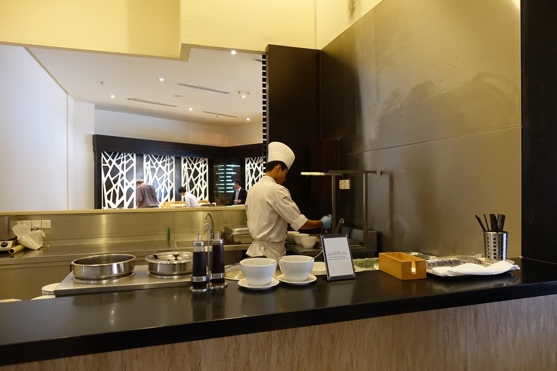 A chef prepares food at a live cooking station in the Malaysian Airlines First Class Lounge.