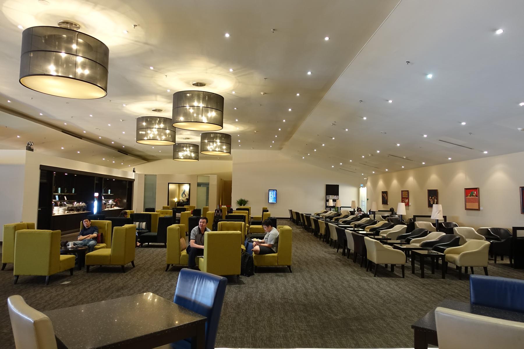 Spacious Malaysian Airlines First Class Lounge at Kuala Lumpur Airport with various seating and guests.