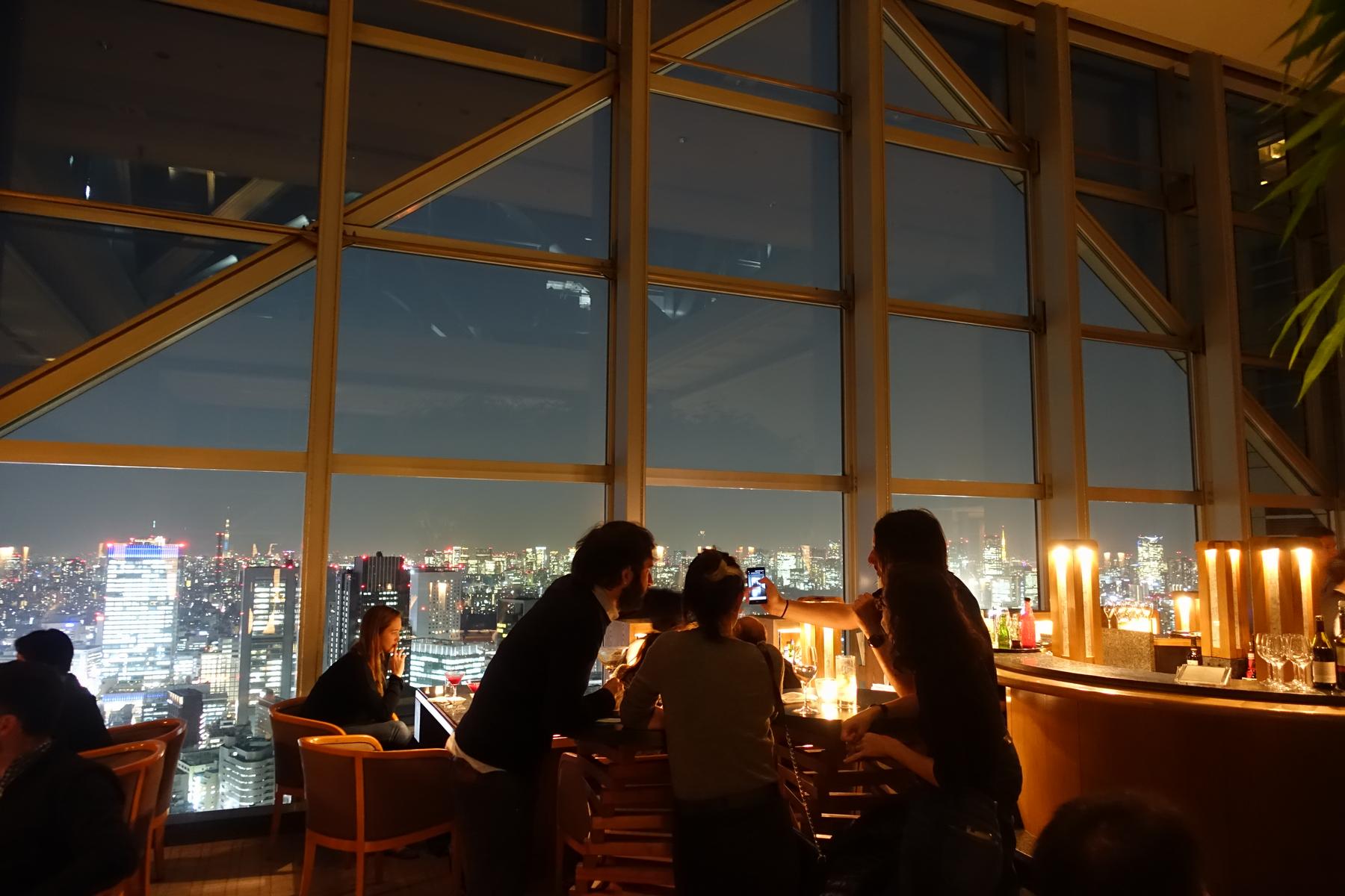 Guests at the Park Hyatt Tokyo's New York Bar enjoy drinks and the city night view.