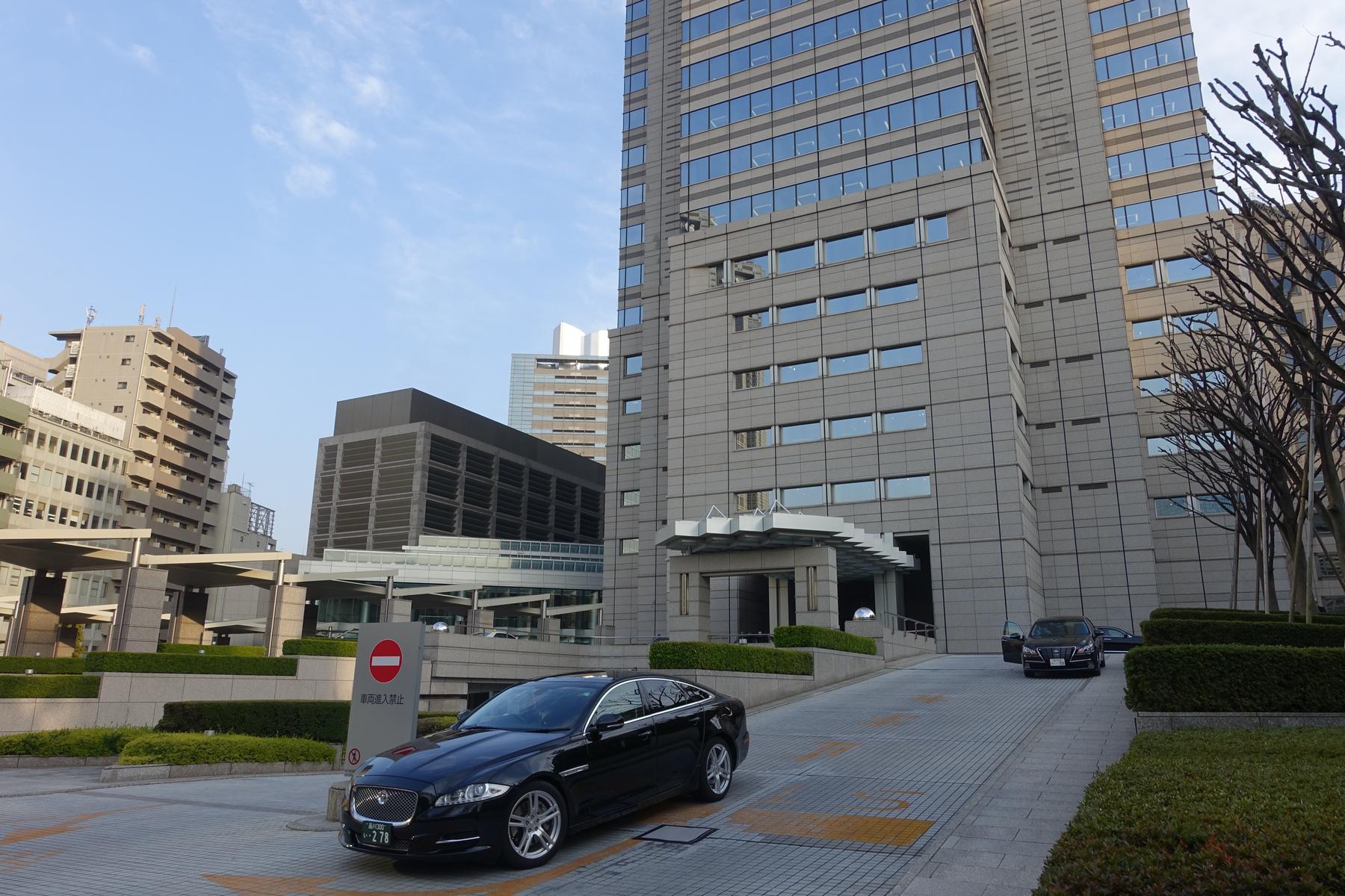 The exterior of the Park Hyatt Tokyo building with a black sedan parked in front.