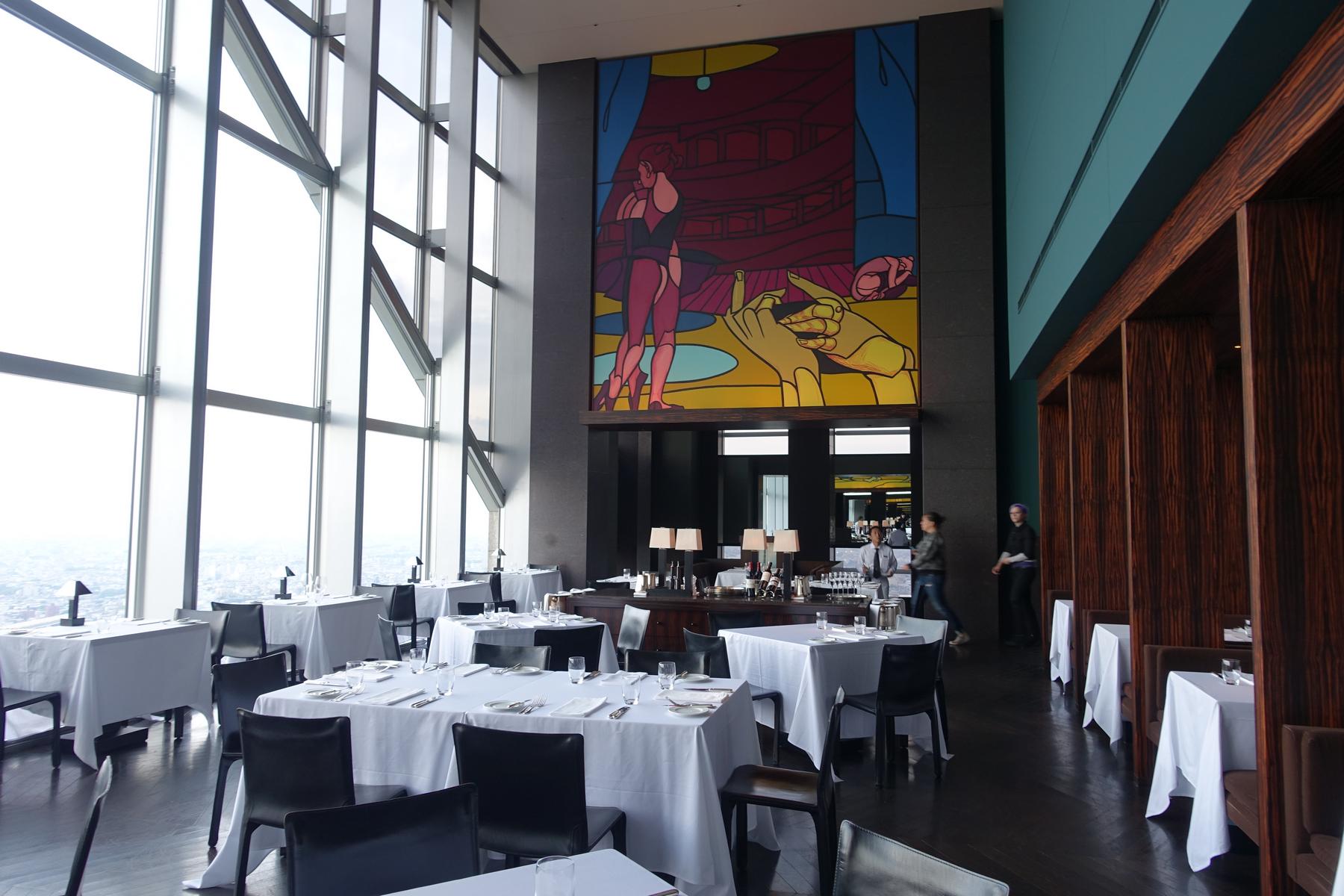 New York Bar at Park Hyatt Tokyo with city views from floor-to-ceiling windows, set dining tables, and a vibrant mural.