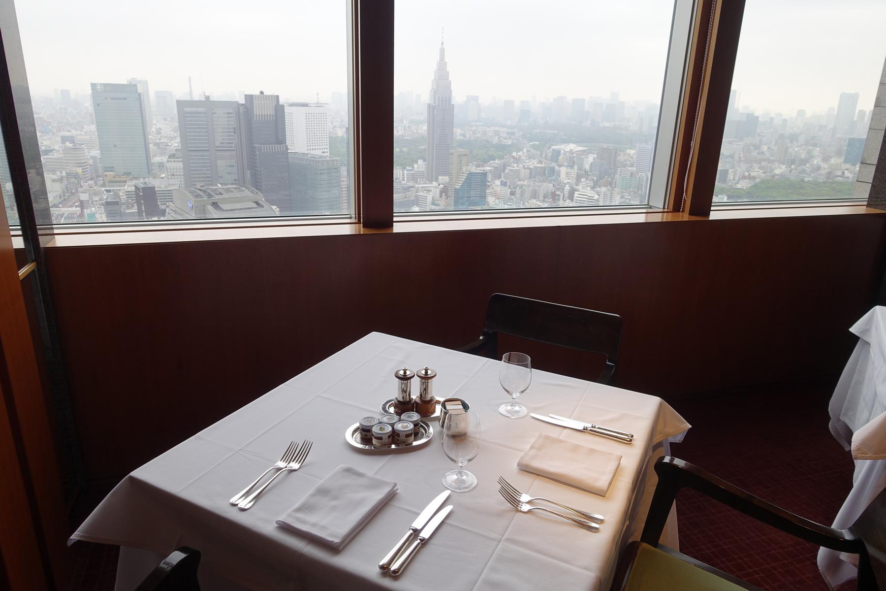 A set dining table overlooking the Tokyo cityscape from a high-rise restaurant.