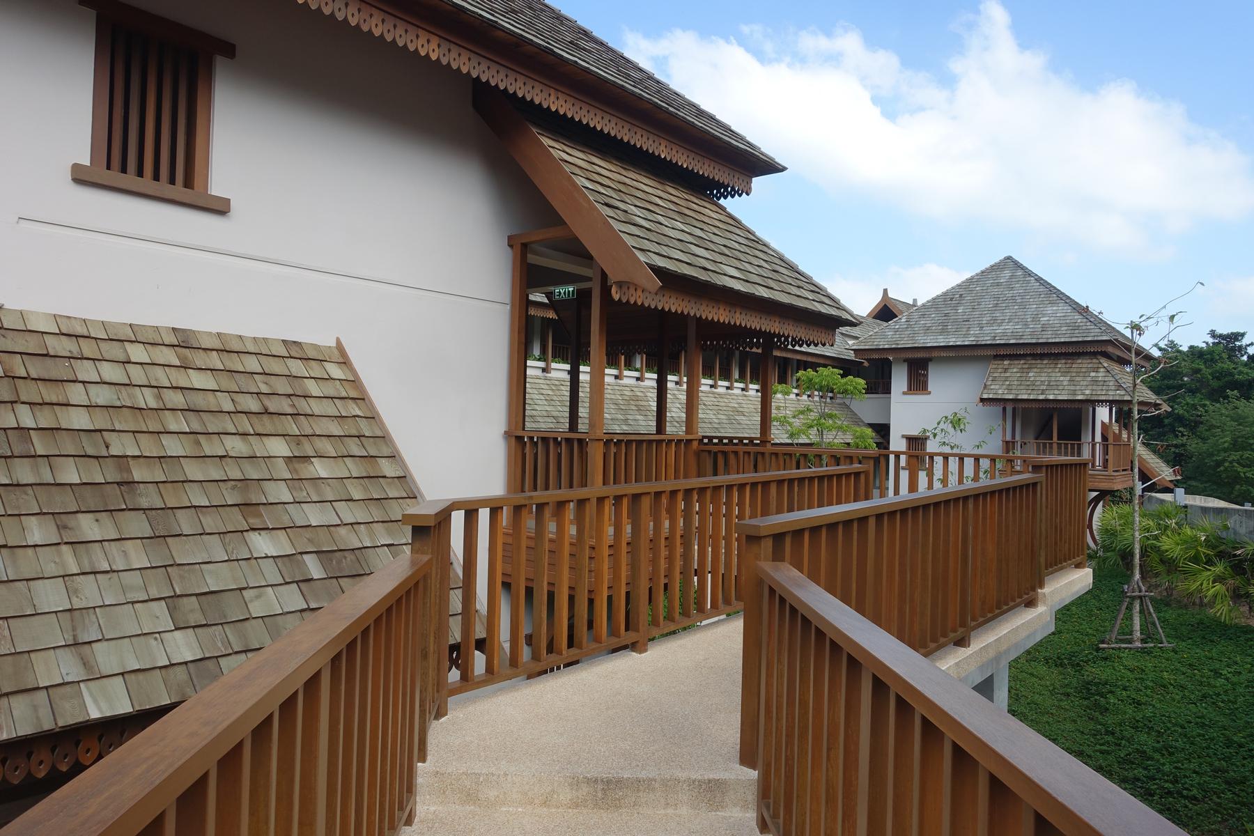 Traditional Thai-style buildings with wooden shingle roofs and connecting elevated walkways.