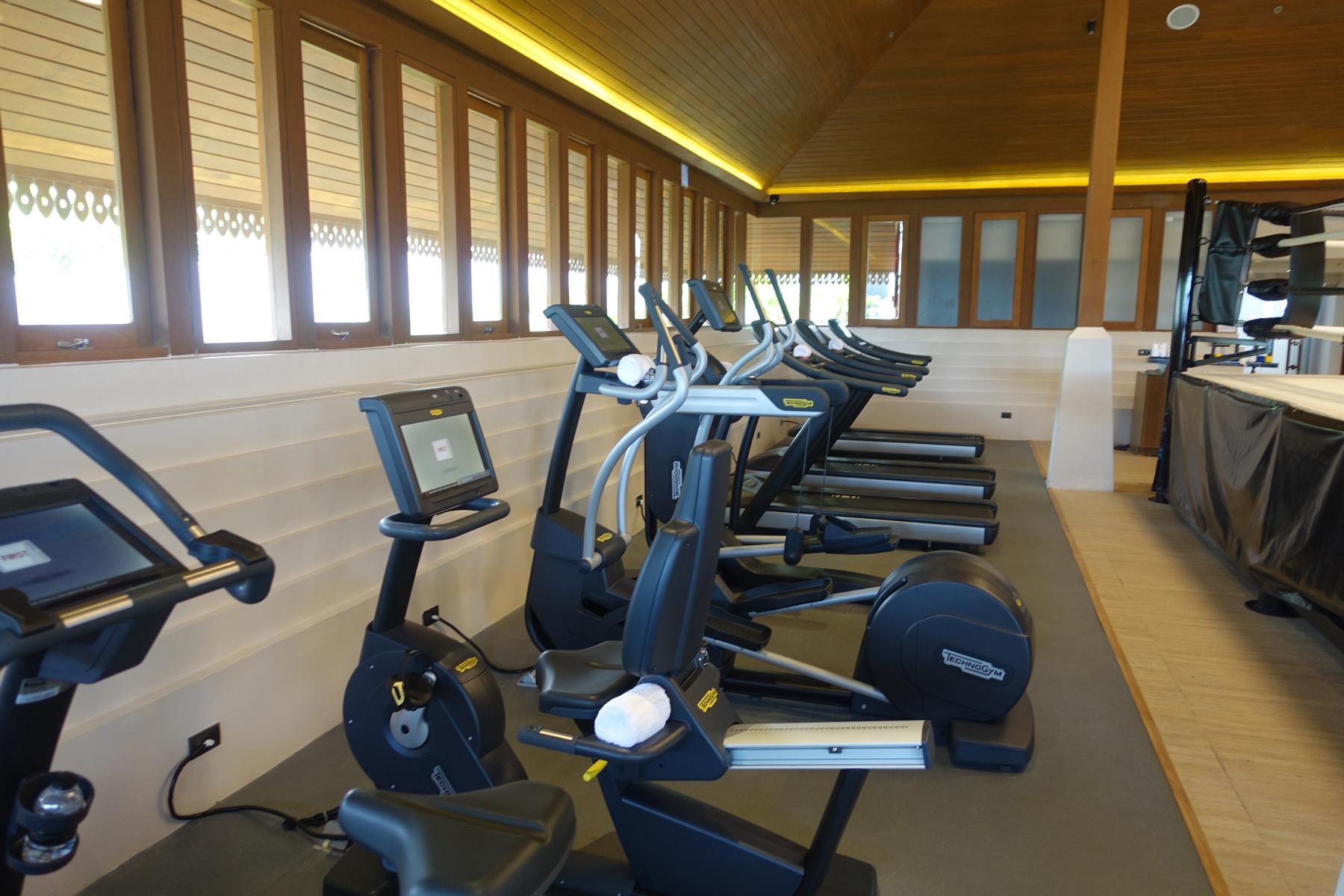 The Ritz Carlton Koh Samui gym, featuring a row of Technogym cardio machines and a boxing ring.