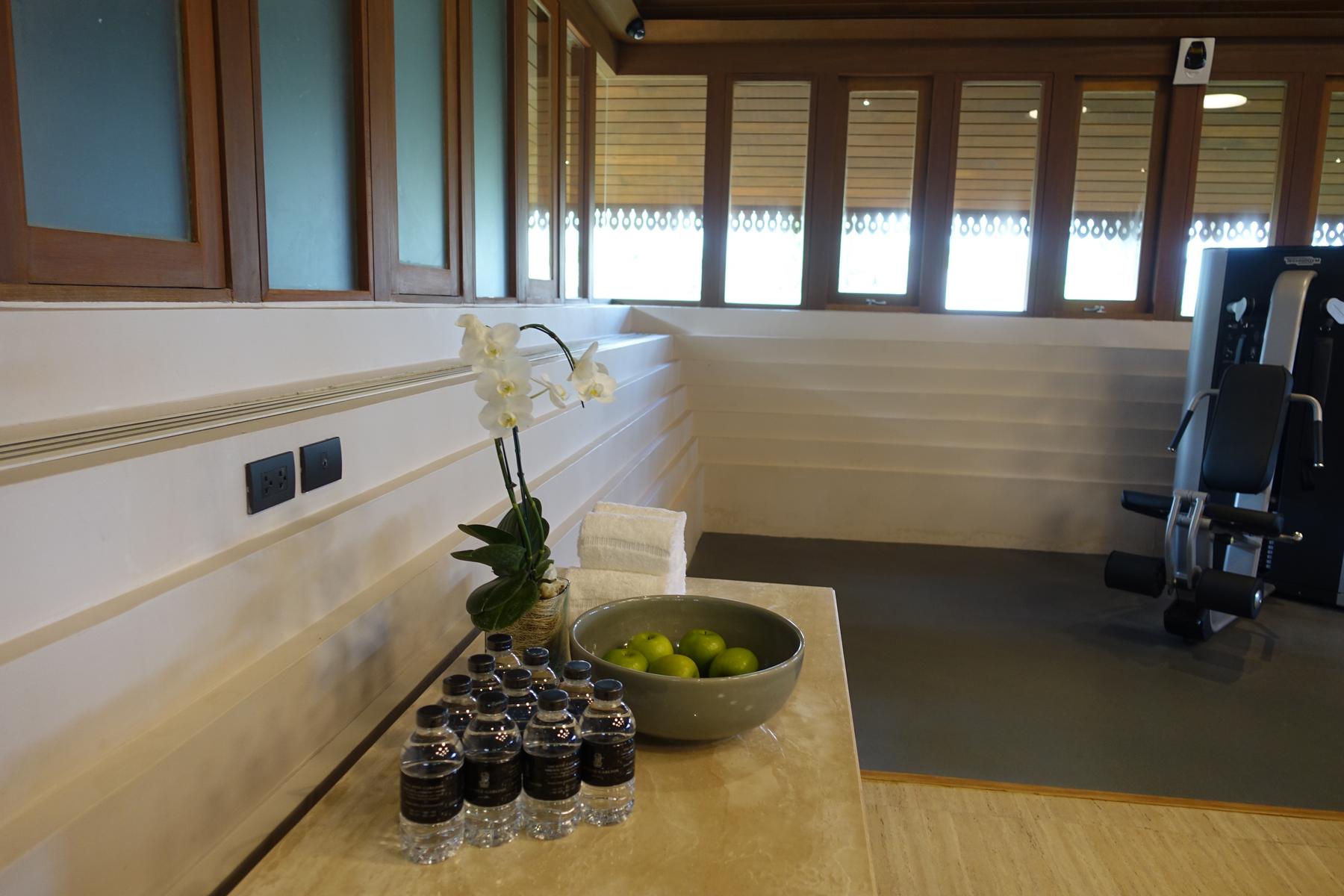 Bottled water, green apples, and an orchid on a counter in a hotel gym.
