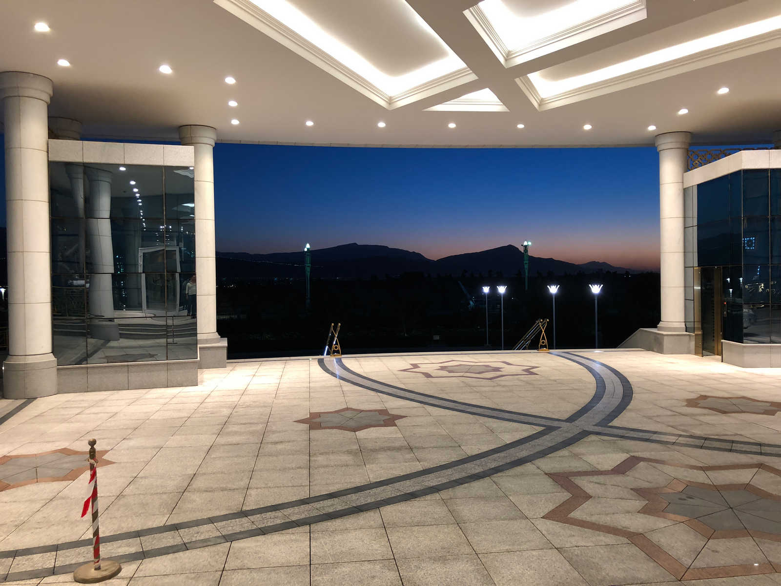 The ornate entrance and patio of the Yyldyz Hotel at twilight, with mountains in the background.