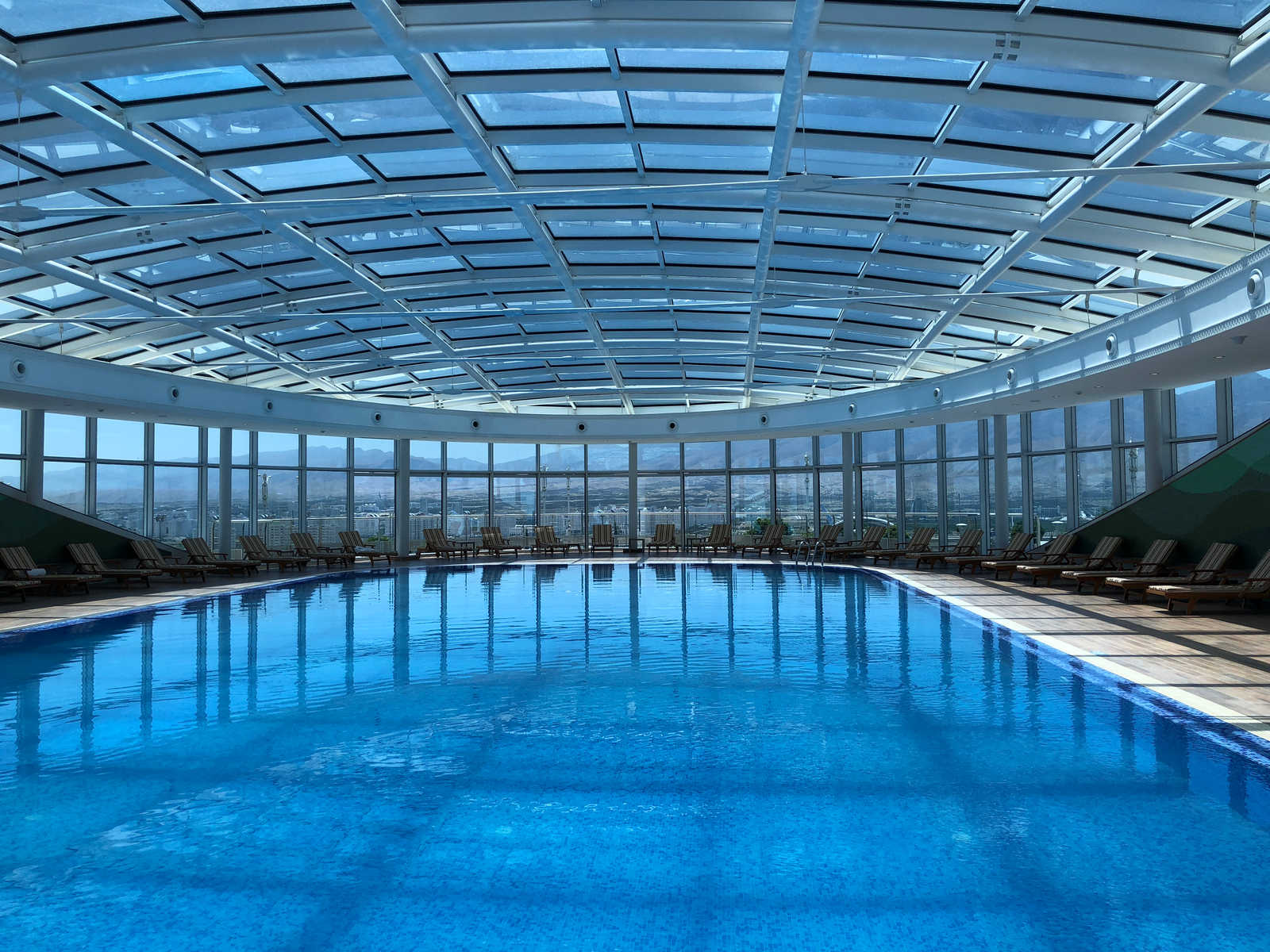 Luxurious indoor pool at Yyldyz Hotel with a glass roof and panoramic city views.