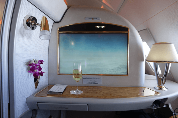 A luxurious Emirates First Class suite featuring a personal screen, champagne, and orchids.
