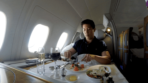 A man dining on a meal with full table service inside an Emirates A380 First Class suite.
