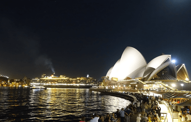 Sydney Opera House and a cruise ship illuminated at night in Sydney Harbour.
