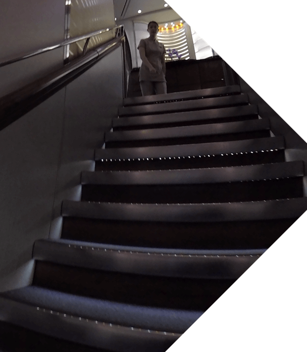 An Emirates flight attendant stands at the top of the A380's onboard staircase.