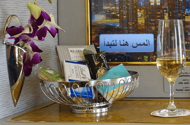 Emirates First Class amenities with champagne, a snack basket, and orchids.
