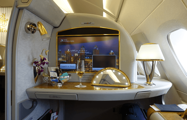 An Emirates A380 First Class suite interior with a large screen, champagne, and luxury amenities.