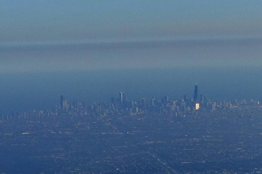 Aerial view of the Chicago skyline featuring the Willis Tower and a prominent skyscraper reflecting sunlight.