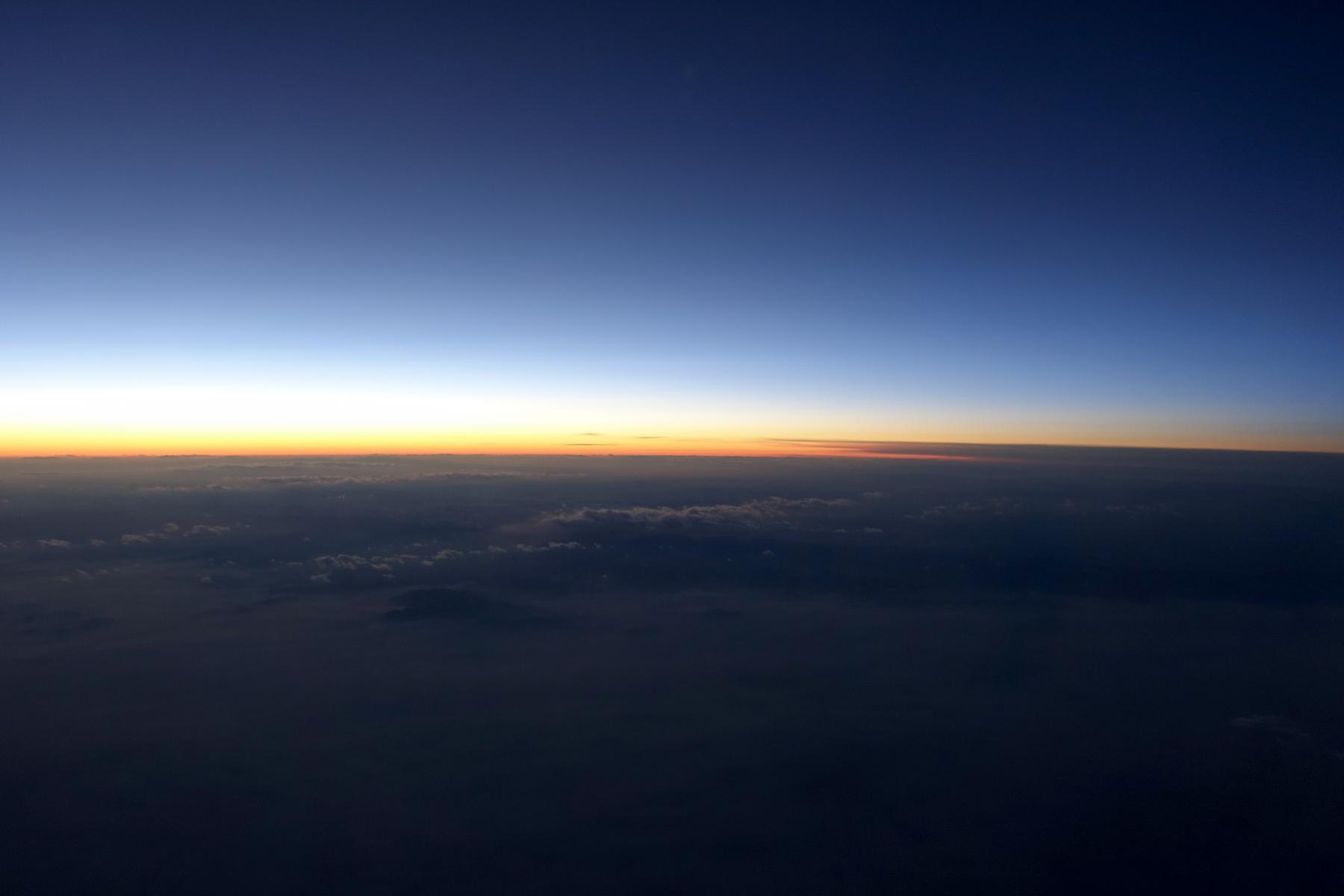 View from an airplane of a sunset over clouds.