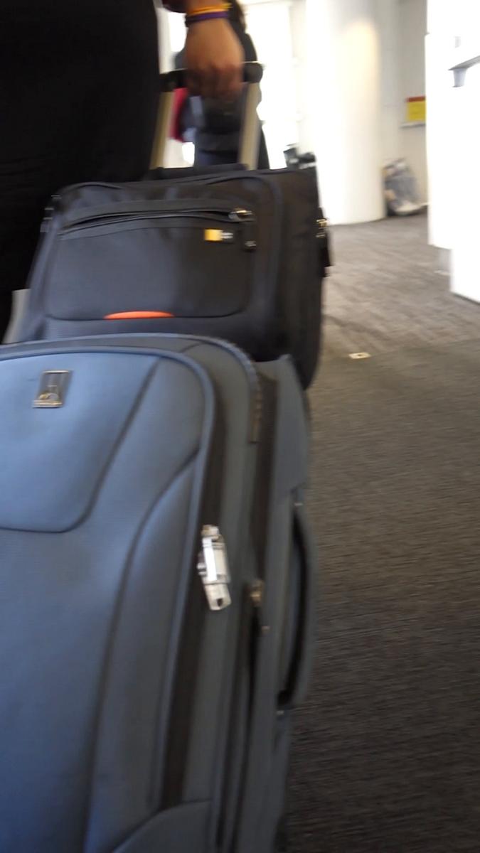 A person pulls two rolling suitcases through an airport terminal.