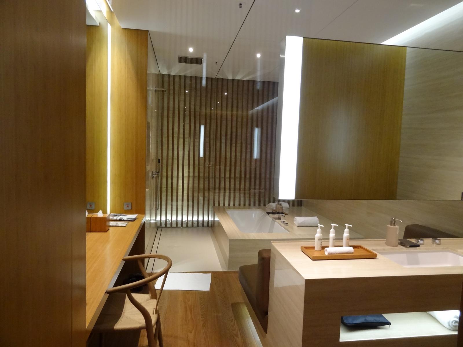 A well-appointed lounge bathroom with a bathtub, walk-in shower, and vanity in warm wood tones.