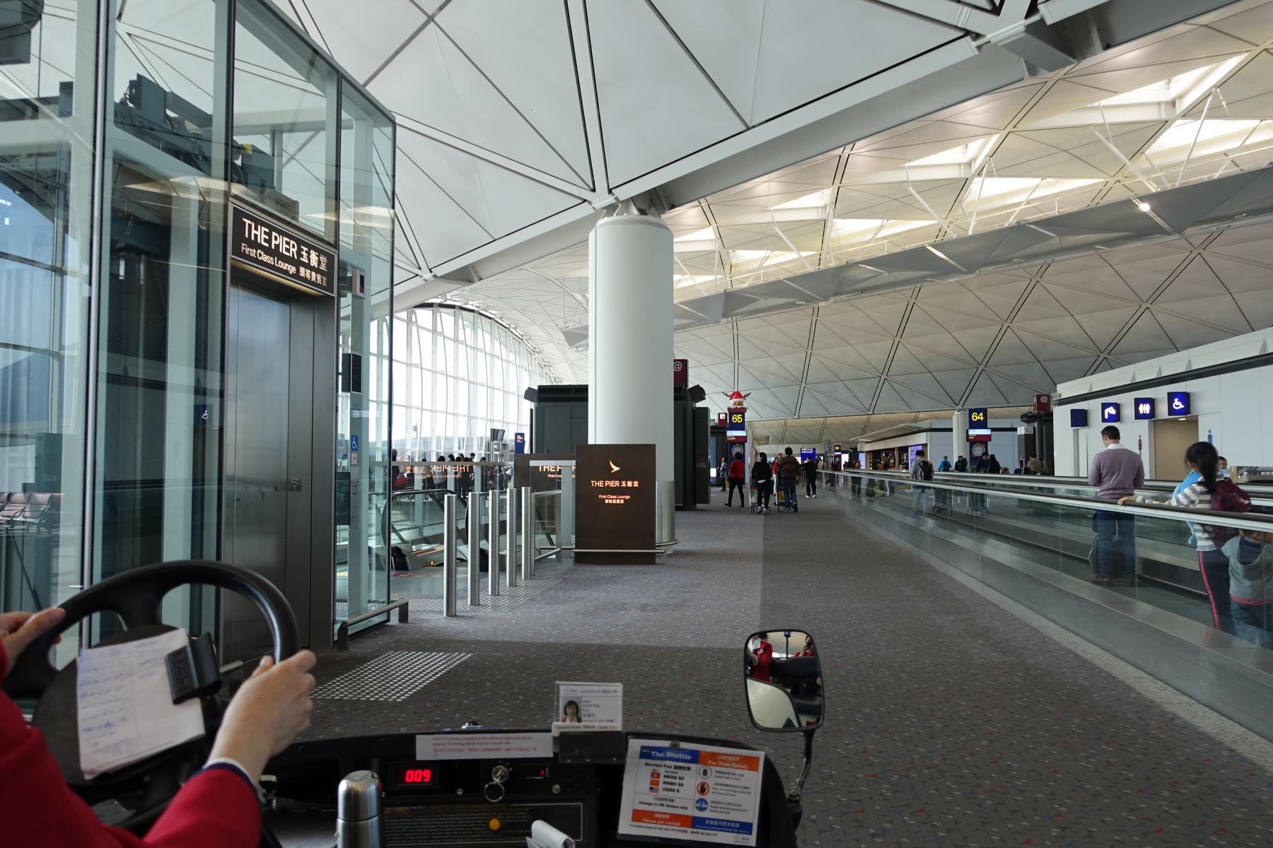 View from a buggy approaching The Pier First Class Lounge entrance in an airport terminal.