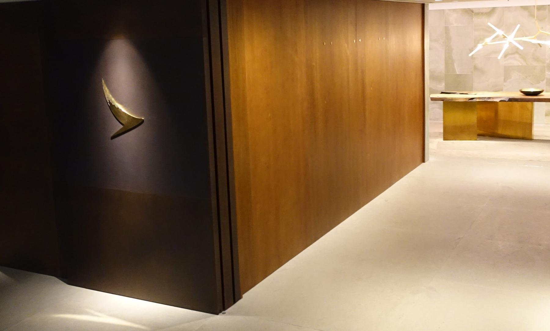 Golden Cathay Pacific logo illuminated on a dark wall within a modern lounge.