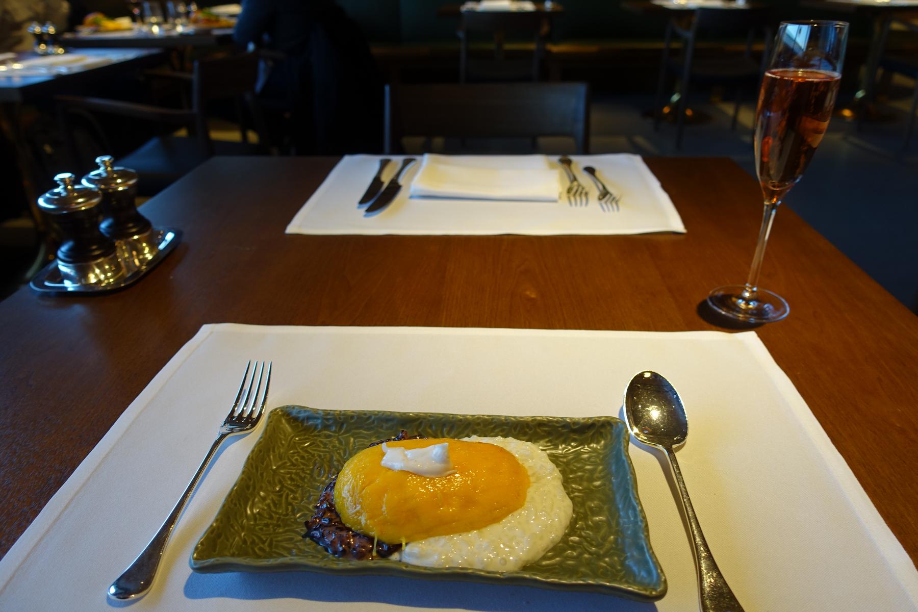 Mango sticky rice dessert and a glass of rosé champagne on a table in a first-class lounge.