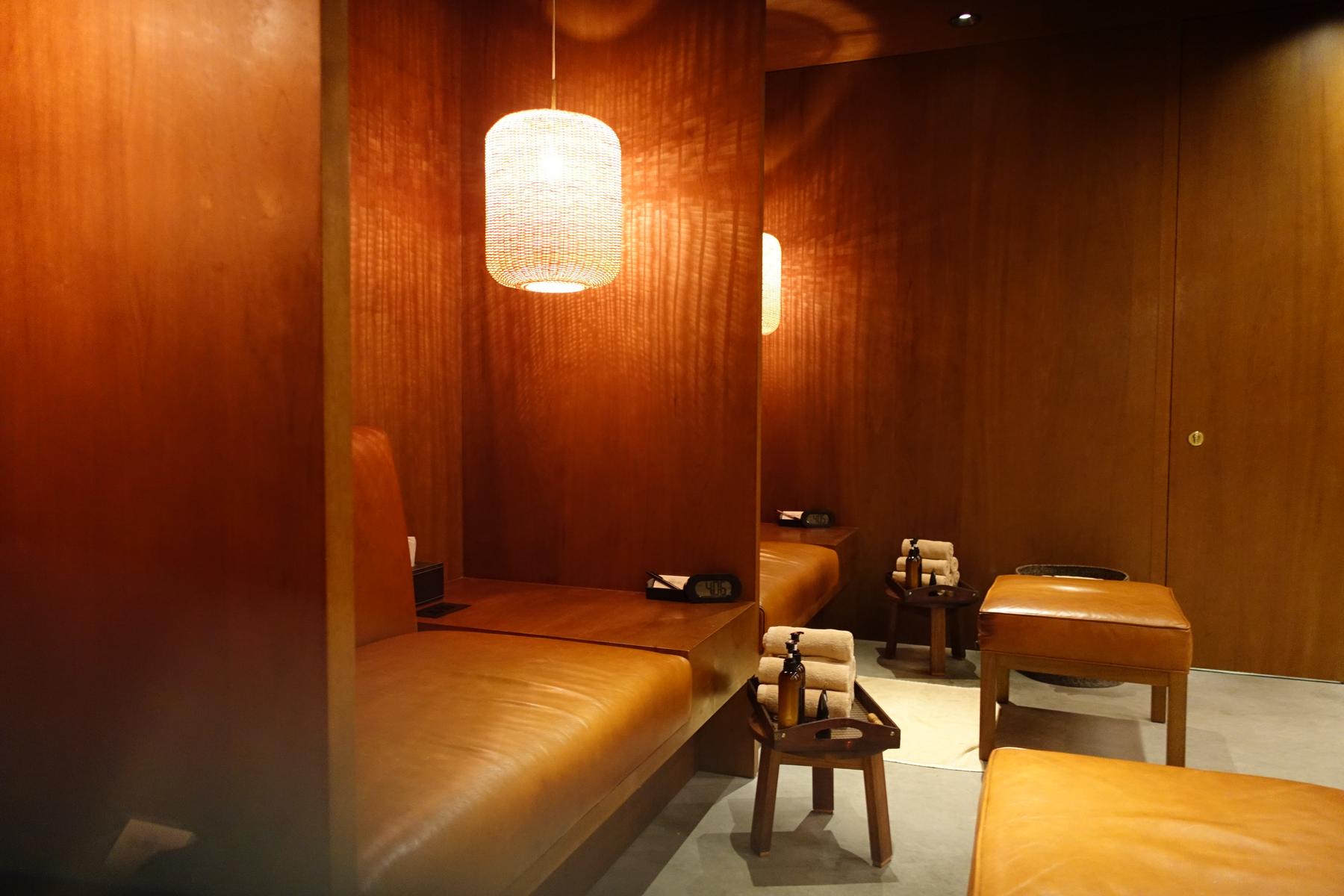 A lounge relaxation room with wood-paneled walls, leather seating, and spa amenities.