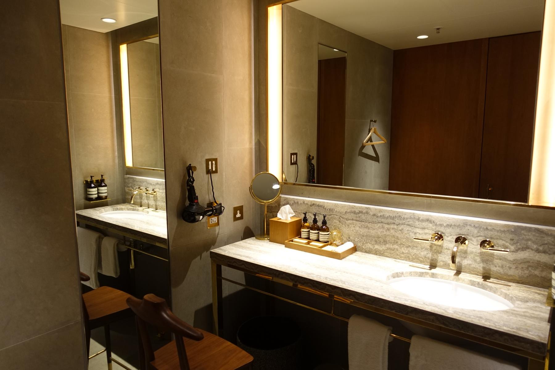 Luxurious private washroom with dual marble vanities, gold fixtures, and Aesop toiletries.