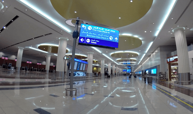 Modern airport terminal with a prominent sign pointing to First Class and Business Class check-in.