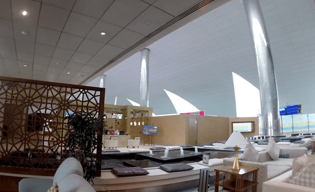 A spacious and elegant Emirates First Class lounge with comfortable seating and a central water feature.
