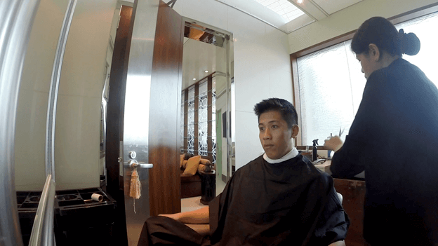 A man gets a haircut from a stylist in a modern salon setting.