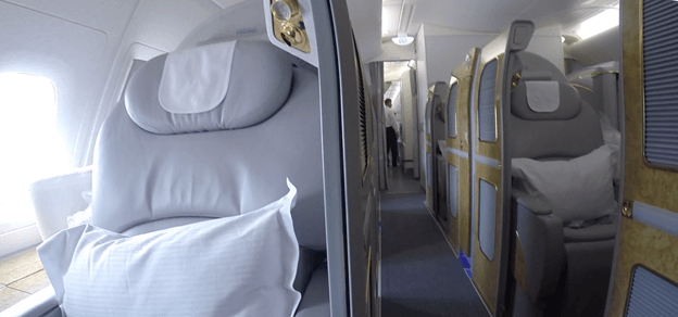 Emirates A380 First Class cabin with private suites featuring gold accents.