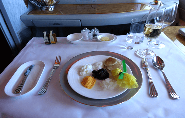 An Emirates First Class dining table is elegantly set with caviar, blinis, and champagne.