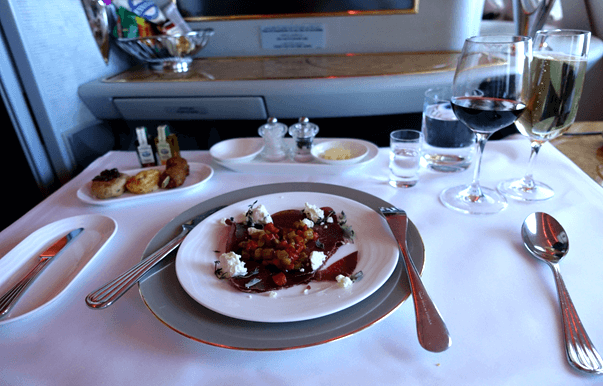 A gourmet meal with wine and champagne is served on a white tablecloth in Emirates First Class.