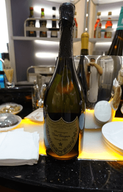 A bottle of Dom Pérignon champagne sits on a dark bar.