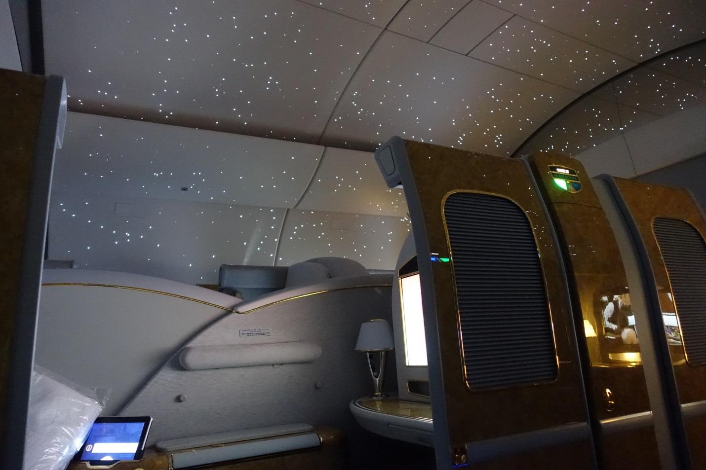 Emirates First Class cabin interior with a starry ceiling and gold-accented private suites.