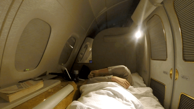 A passenger sleeping in a luxurious Emirates A380 First Class private suite.
