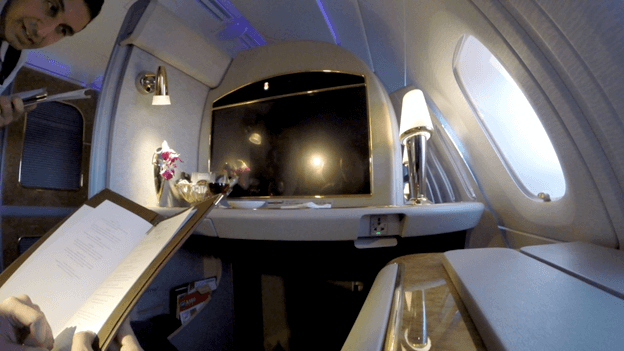 A passenger reviews a menu in their Emirates First Class suite on an A380.