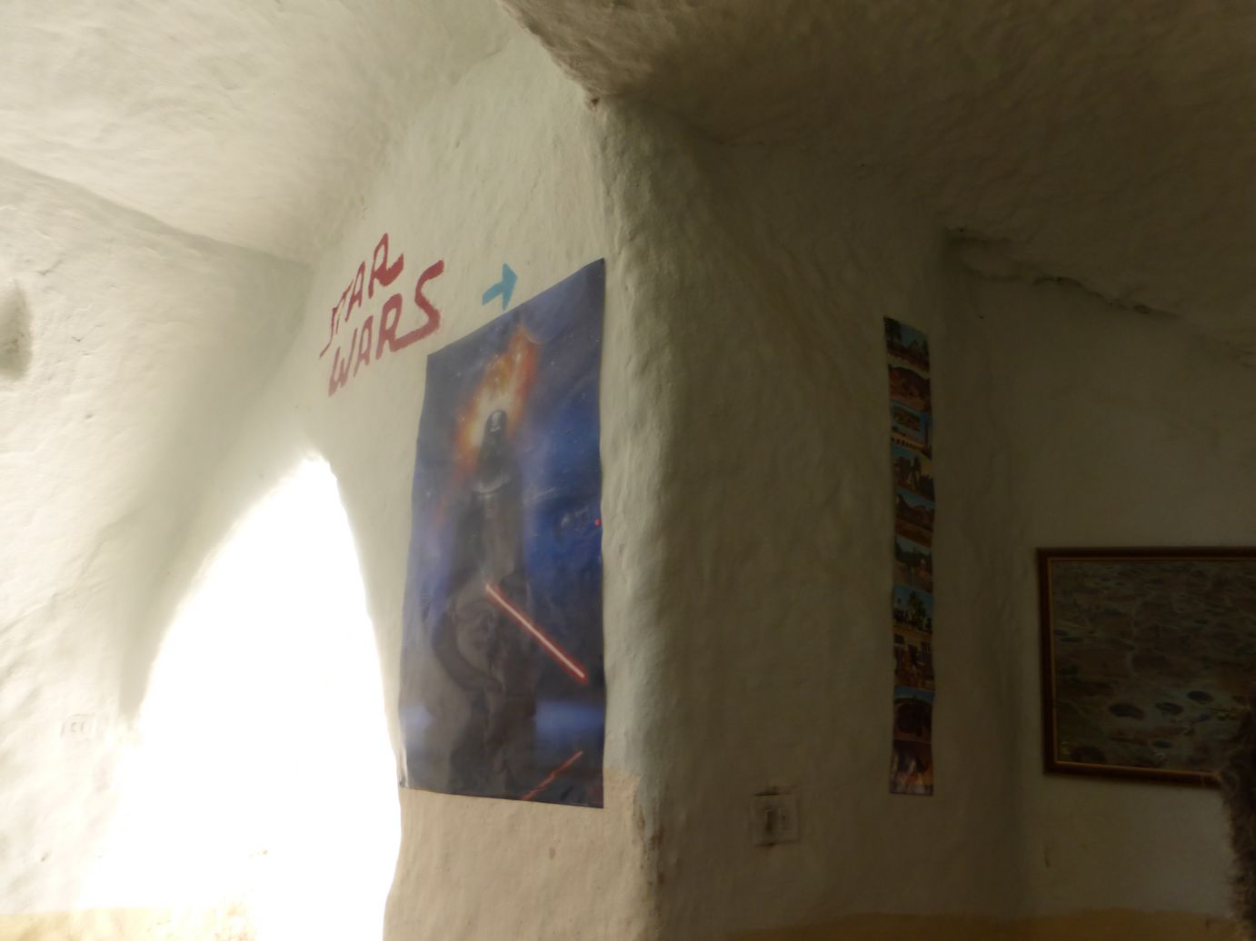 A Star Wars sign and Darth Vader poster on the rough white wall of a Tunisian film set.