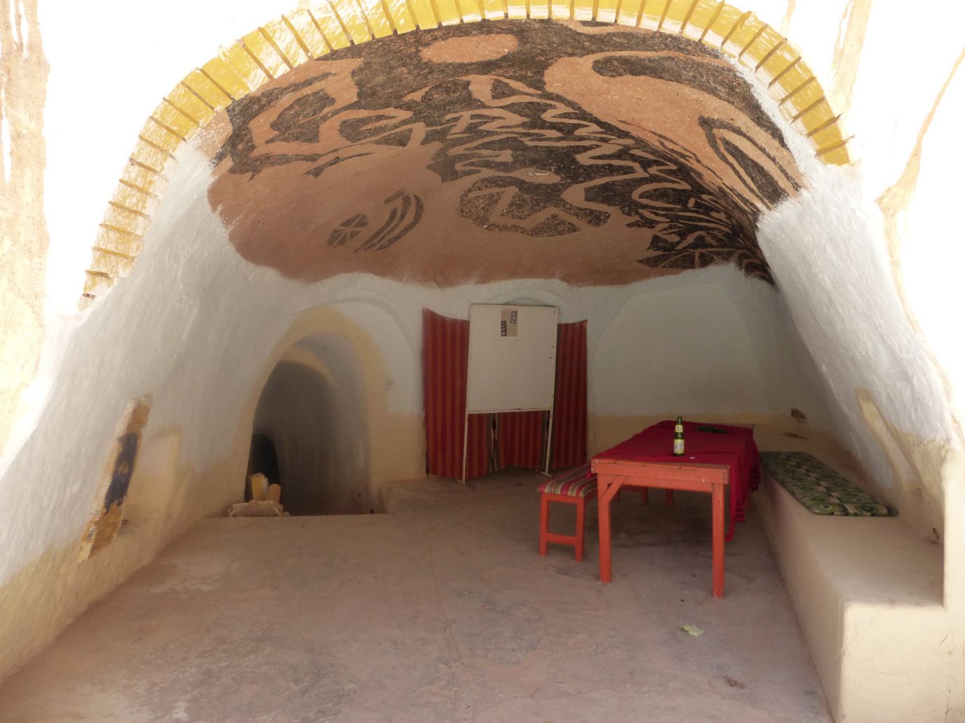 A domed, cave-like room, part of a Star Wars set, with a painted ceiling, red table, and benches.