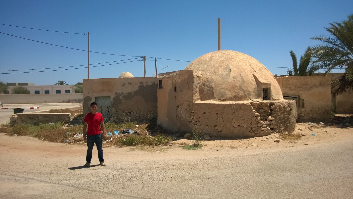 A traveler stands on a dusty road in front of an iconic domed structure from the Star Wars sets in Tunisia.