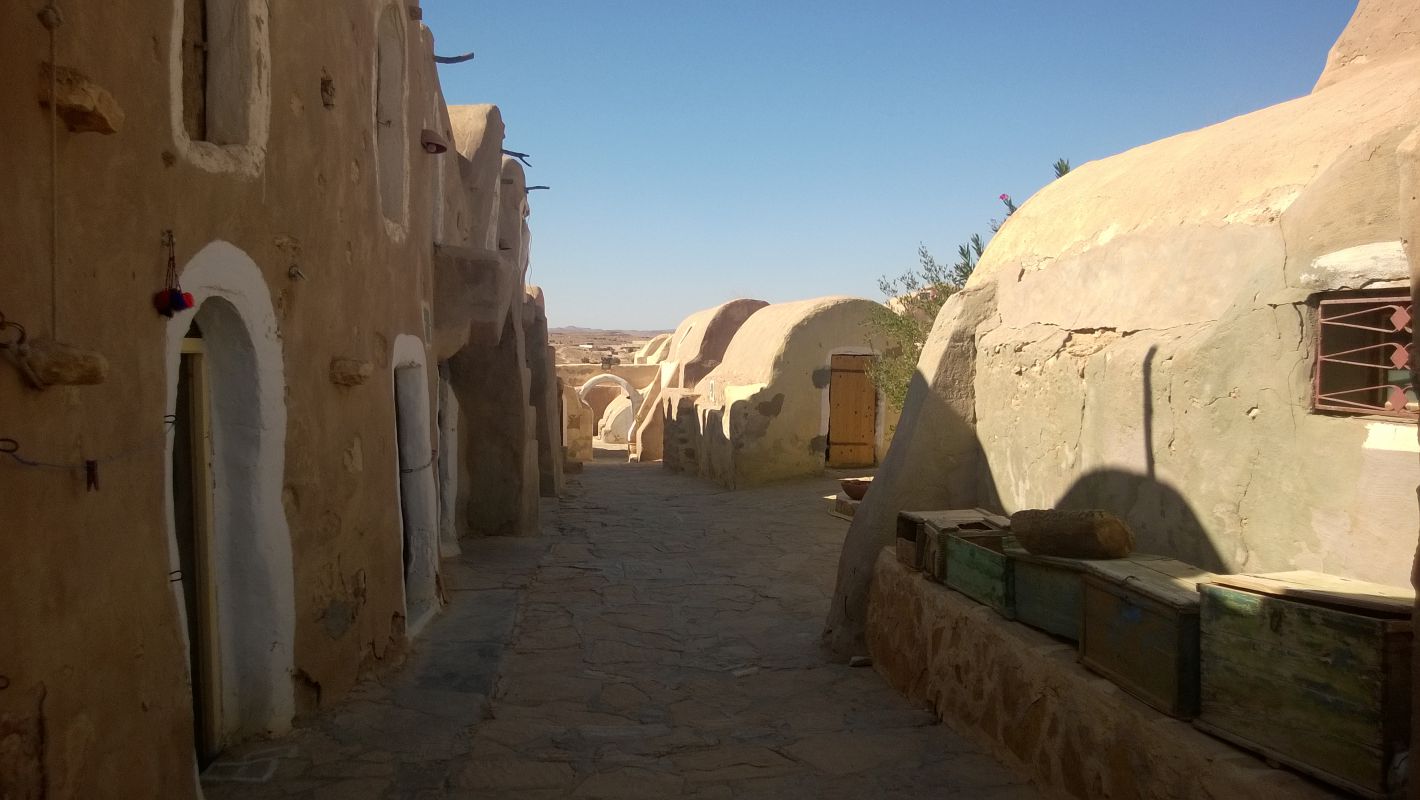 A village street lined with sand-colored adobe buildings, reminiscent of Star Wars sets.
