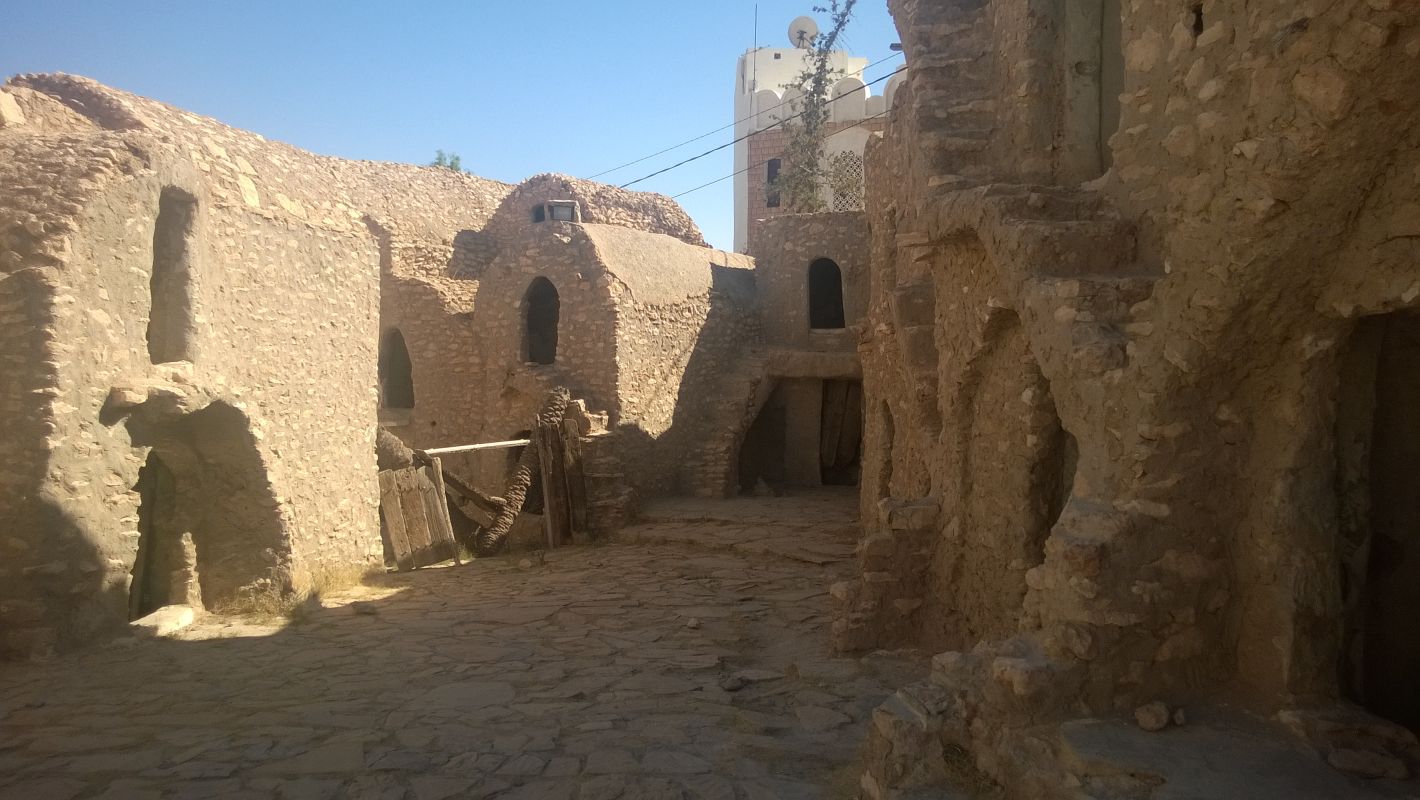 Stone buildings with arched openings line a sunny courtyard at a Star Wars set in Tunisia.