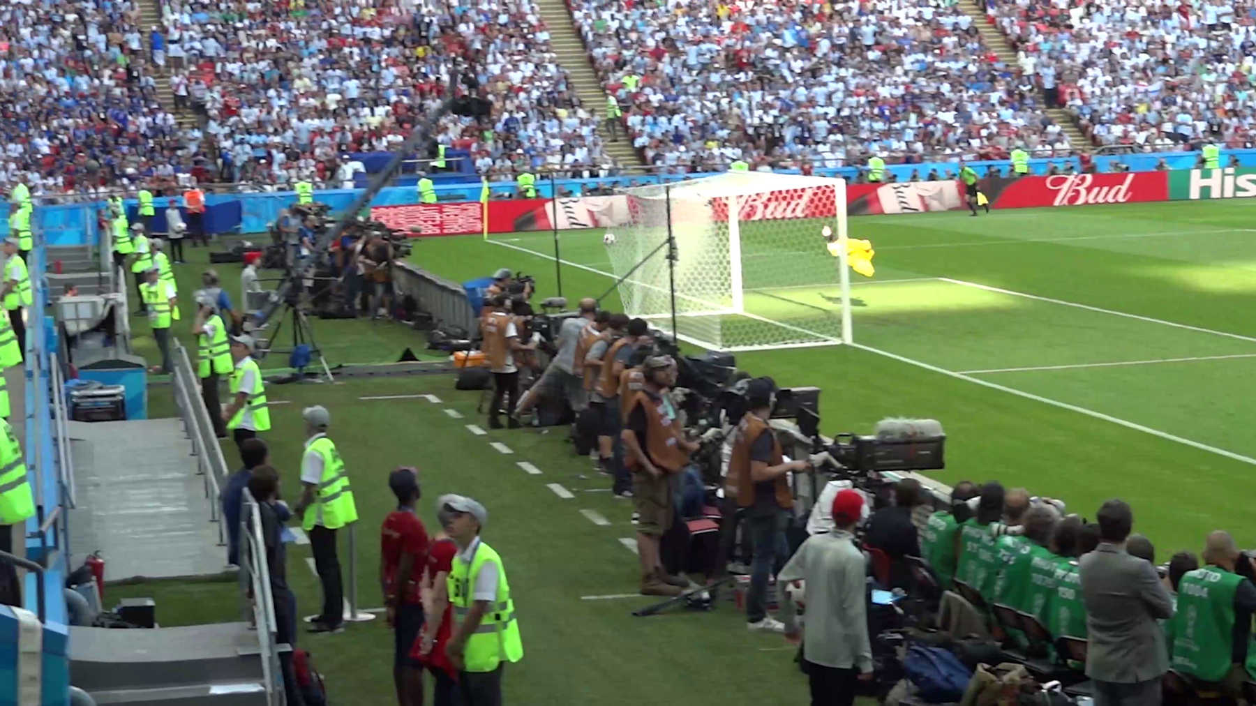 A crowded stadium view of the 2018 World Cup match between Argentina and France, with a goalkeeper by the goal and media personnel along the sideline.