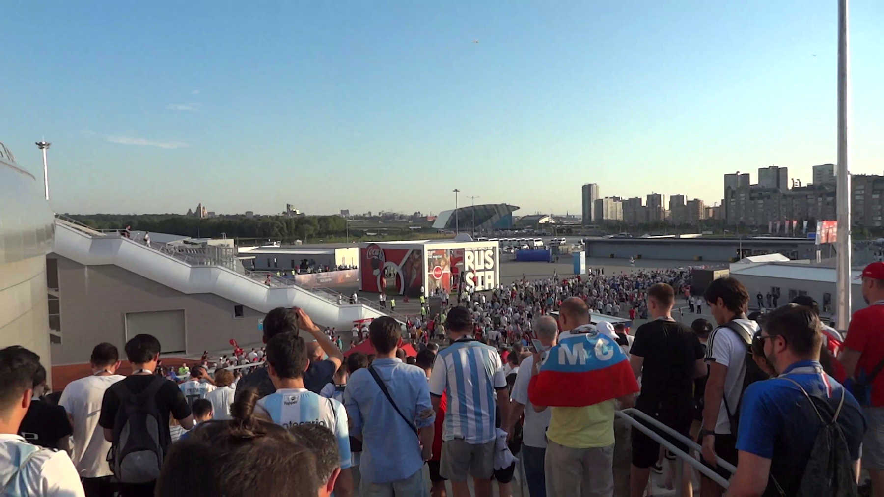 A large crowd of football fans, some wearing Argentina jerseys, gathers outside a stadium in Russia during the 2018 World Cup.