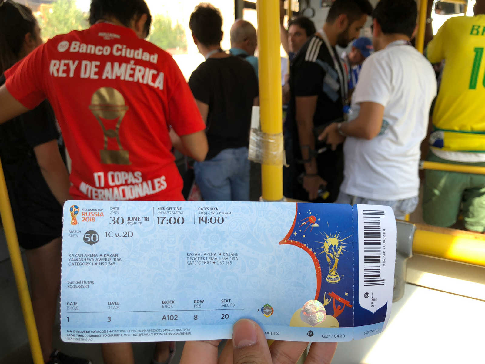 A hand holds a 2018 World Cup ticket for the Argentina vs France match, with fans visible in the background.
